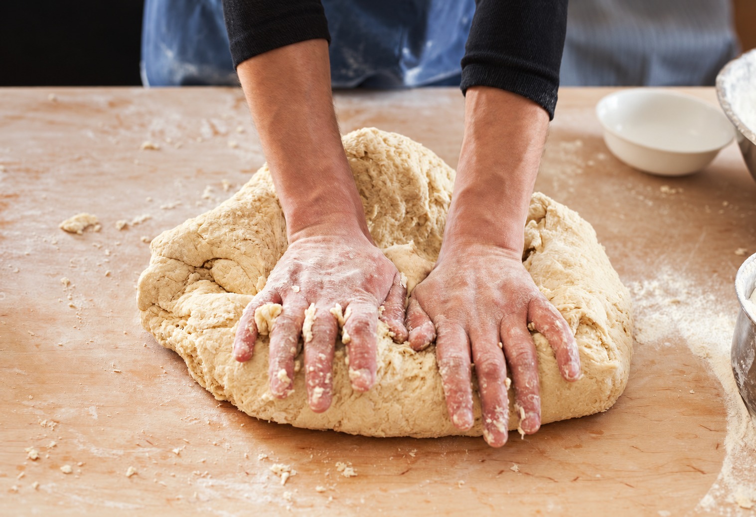Hands kneading dough on a flour-dusted work surface